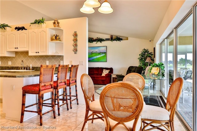 dining room featuring light tile patterned floors and vaulted ceiling