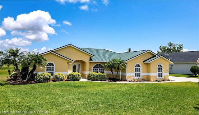 ranch-style home with stucco siding, metal roof, and a front lawn
