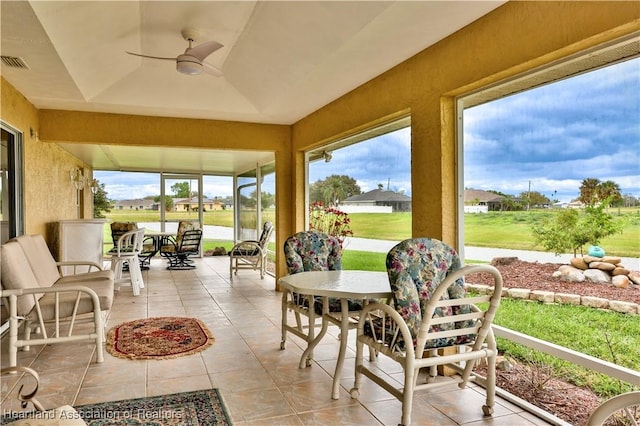 sunroom with ceiling fan, visible vents, a raised ceiling, and a wealth of natural light