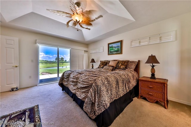 carpeted bedroom with a tray ceiling, baseboards, access to exterior, and a ceiling fan