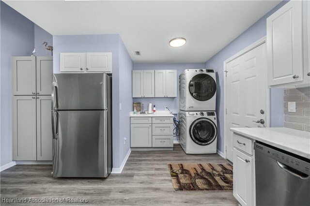 laundry area with light hardwood / wood-style floors and stacked washer / drying machine