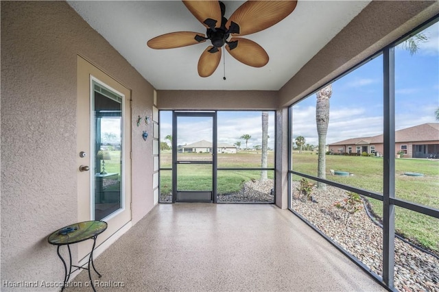 unfurnished sunroom featuring ceiling fan