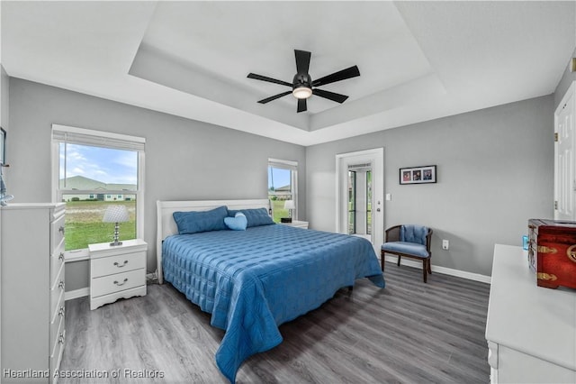 bedroom featuring ceiling fan, a raised ceiling, and wood-type flooring