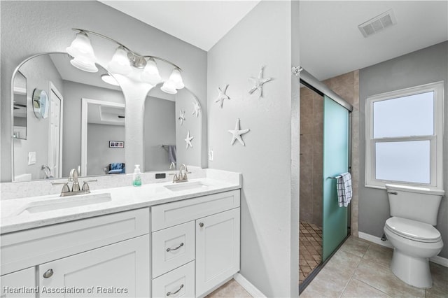 bathroom with tile patterned flooring, vanity, toilet, and a tile shower