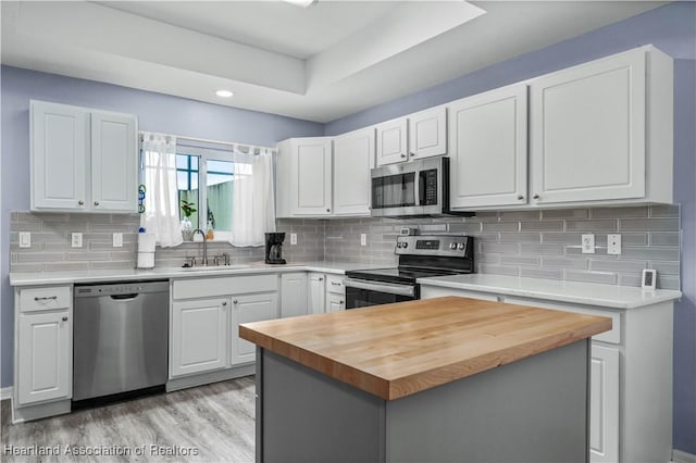 kitchen featuring wood counters, appliances with stainless steel finishes, white cabinets, and sink