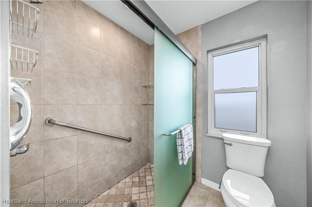 bathroom with tile patterned flooring, toilet, and a shower with shower door