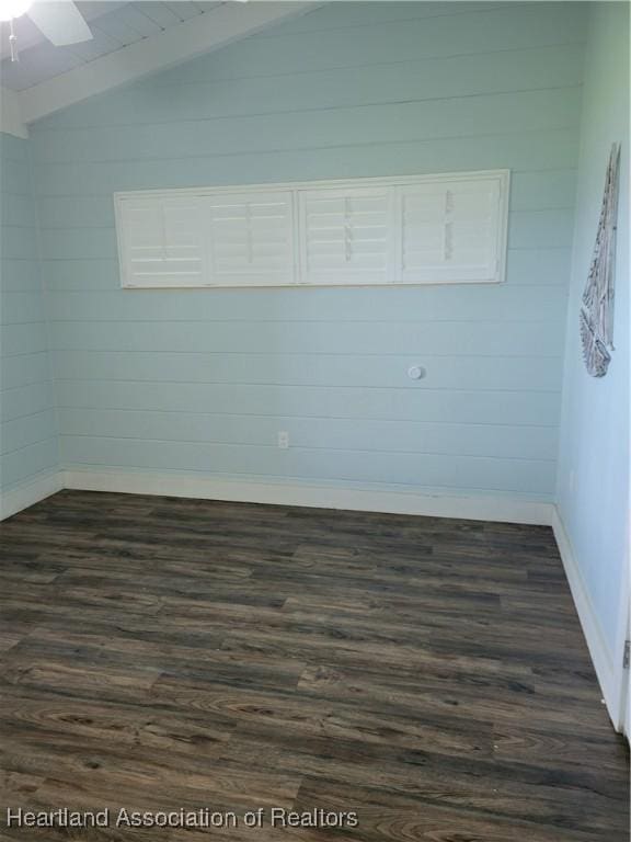 spare room featuring lofted ceiling with beams, ceiling fan, and dark wood-type flooring