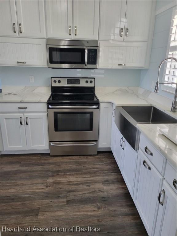 kitchen with sink, stainless steel appliances, light stone counters, dark hardwood / wood-style floors, and white cabinets