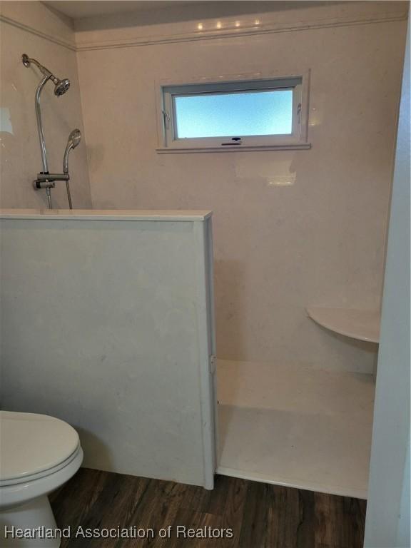 bathroom featuring a shower, hardwood / wood-style floors, and toilet