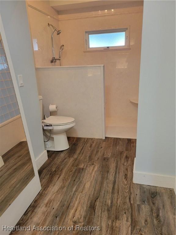 bathroom with hardwood / wood-style flooring, toilet, and walk in shower