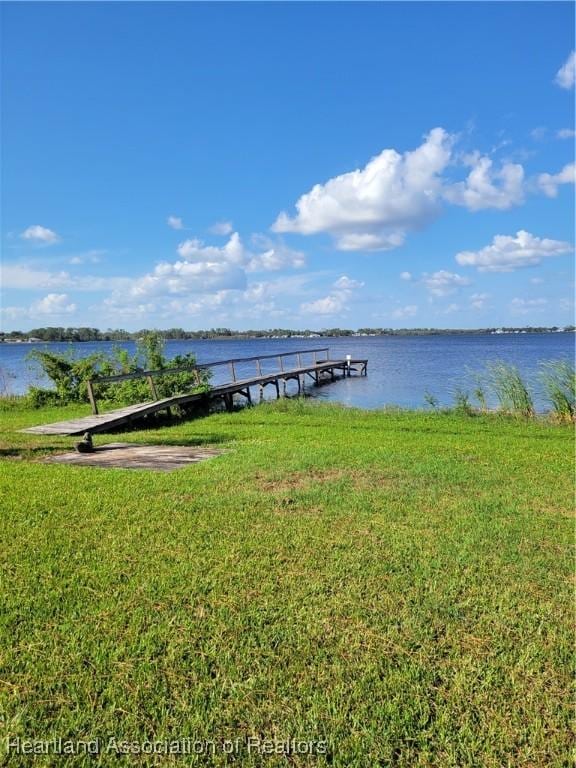 dock area with a water view and a yard