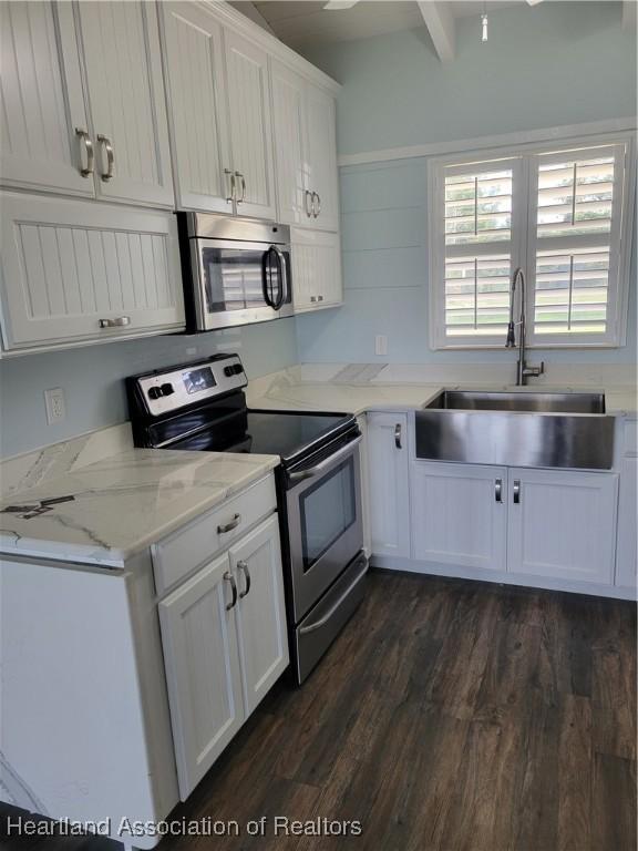 kitchen featuring white cabinets, sink, stainless steel appliances, and beamed ceiling