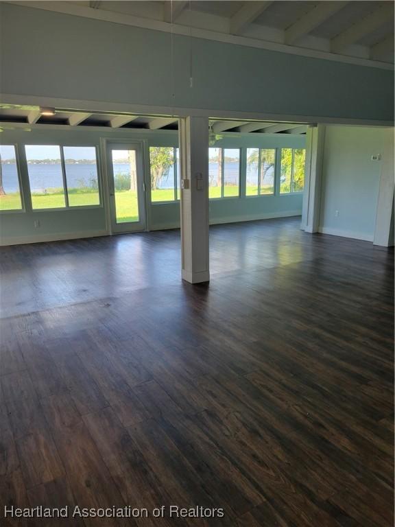 spare room featuring beam ceiling and dark hardwood / wood-style floors