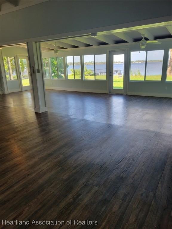 spare room with beamed ceiling, a water view, ceiling fan, and dark hardwood / wood-style floors