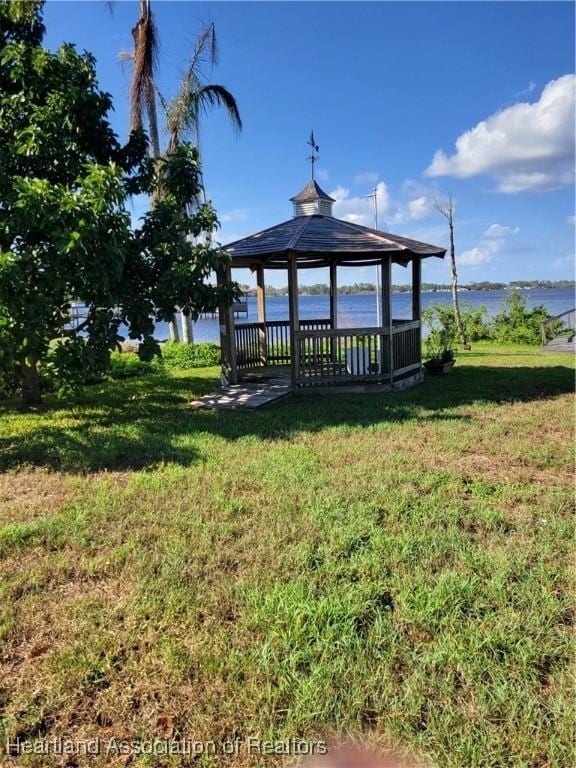 view of dock with a gazebo, a yard, and a water view