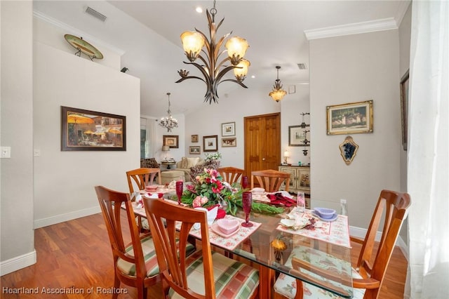 dining room with lofted ceiling, a notable chandelier, ornamental molding, and hardwood / wood-style floors