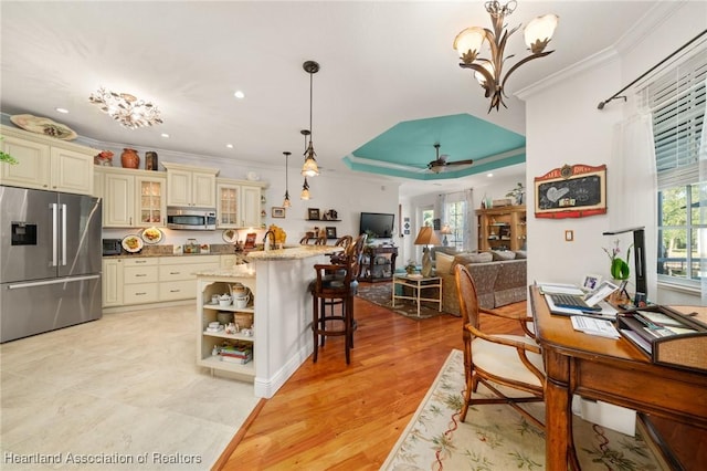 kitchen featuring pendant lighting, a kitchen breakfast bar, light stone counters, stainless steel appliances, and cream cabinets