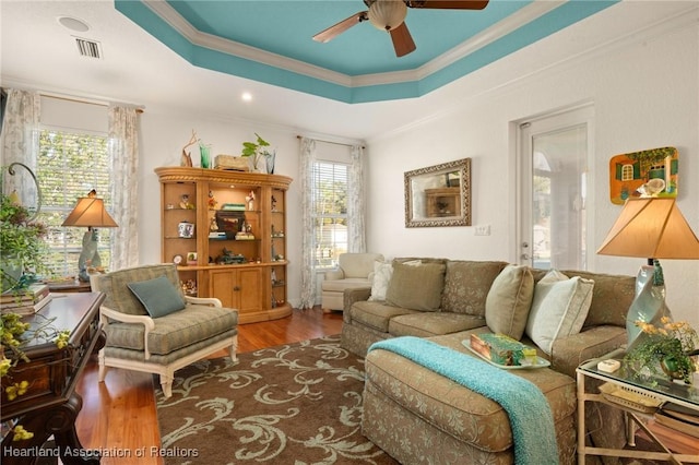 sitting room with hardwood / wood-style floors, a tray ceiling, and ornamental molding