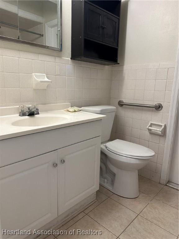 bathroom with toilet, vanity, tile patterned flooring, and tile walls