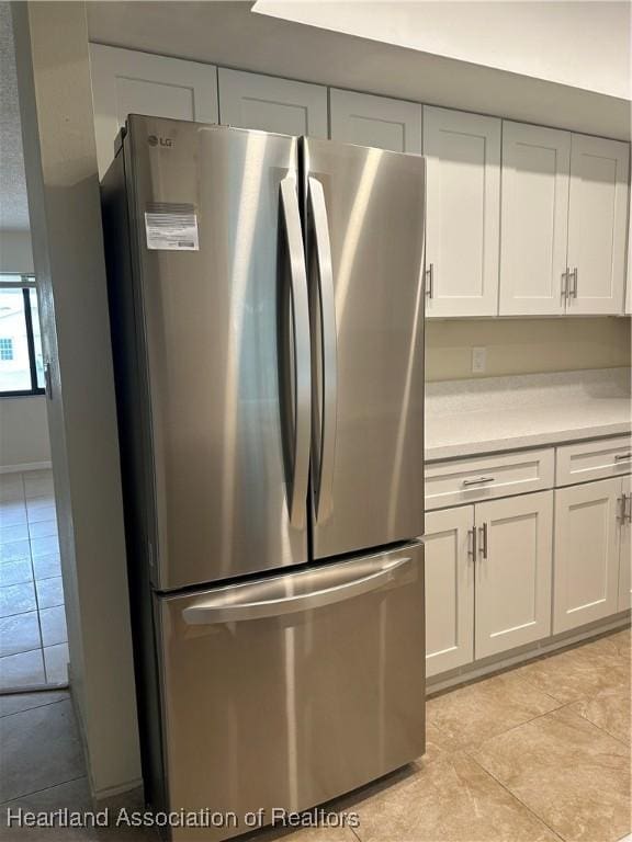 kitchen featuring white cabinets, stainless steel refrigerator, and light tile patterned flooring