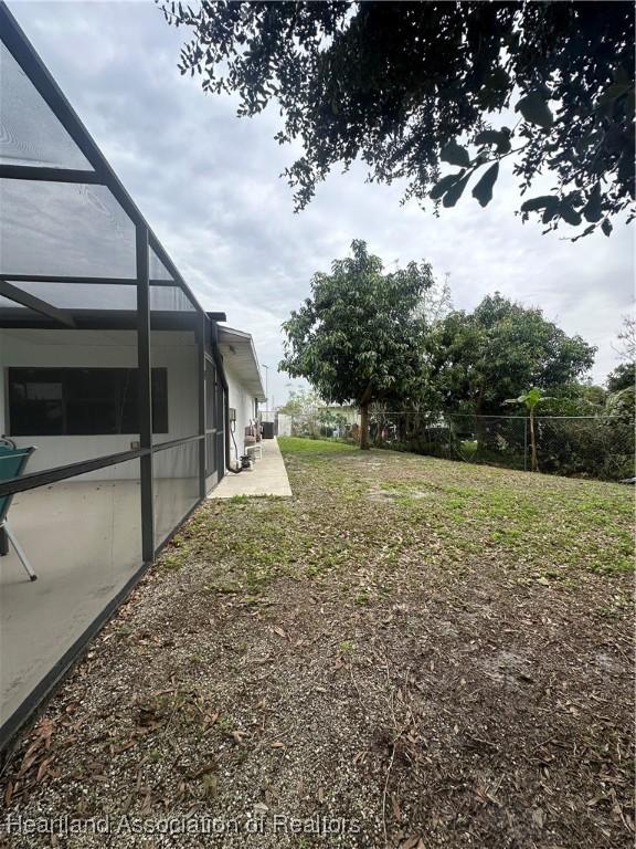 view of yard featuring glass enclosure and a patio area