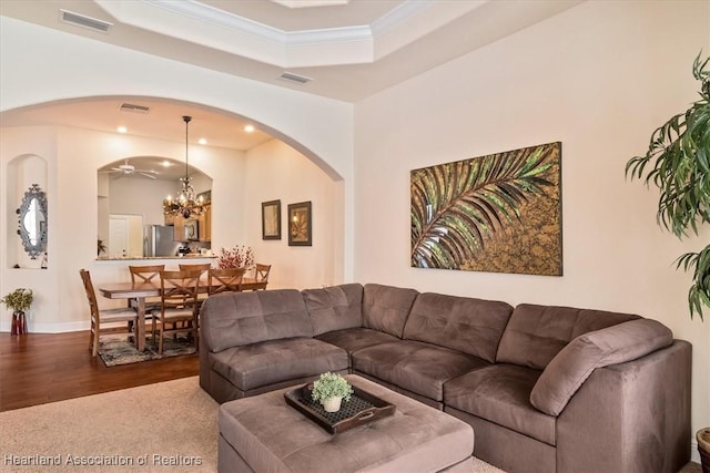 5220 Haw Rd, Sebring, FL 33875 - living room with arched walkways, crown molding, a chandelier, a tray ceiling, and wood finished floors