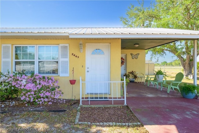 2443 W Newton Rd, Avon Park, FL 33825 - view of exterior entry with an attached carport, stucco siding, and metal roof