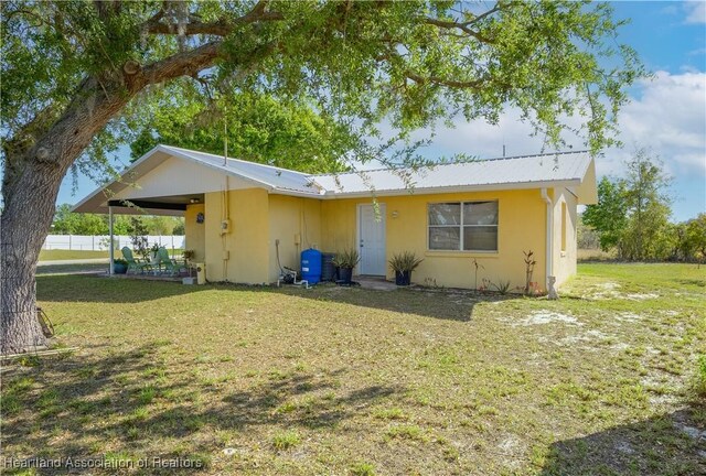 2443 W Newton Rd, Avon Park, FL 33825 - view of front of house featuring a front lawn, metal roof, a carport, and stucco siding