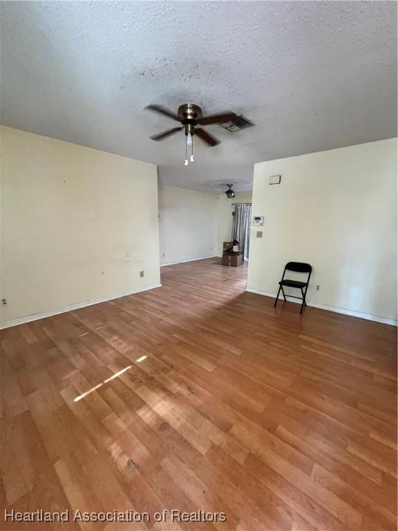 1801 Colmar Ave, Sebring, FL 33870 - unfurnished living room with a ceiling fan, light wood-style flooring, a textured ceiling, and baseboards