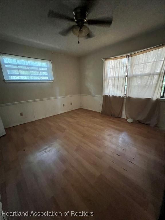 1801 Colmar Ave, Sebring, FL 33870 - empty room with a wainscoted wall, a ceiling fan, and wood finished floors
