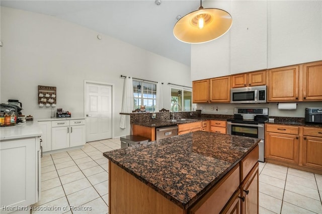 kitchen featuring a high ceiling, a center island, stainless steel appliances, and light tile patterned flooring