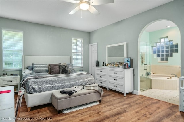 bedroom featuring ceiling fan, light hardwood / wood-style floors, and ensuite bath