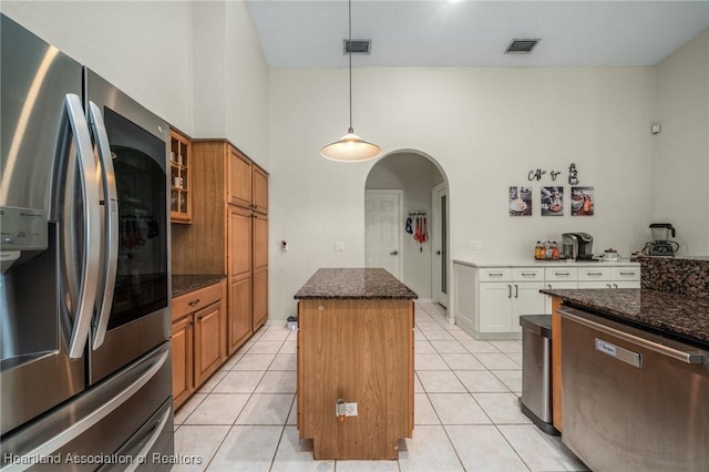 kitchen featuring white cabinetry, a center island, dark stone counters, decorative light fixtures, and appliances with stainless steel finishes