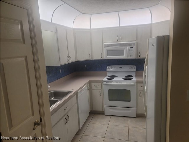 kitchen with light tile patterned flooring, sink, white cabinets, and white appliances