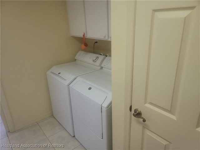 clothes washing area featuring cabinets, washer and dryer, and light tile patterned floors