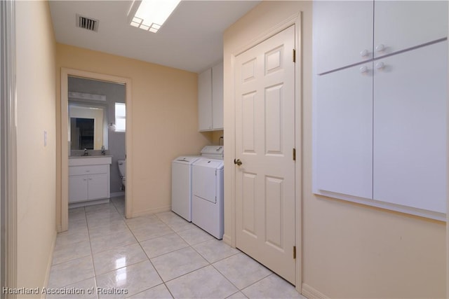 laundry area with cabinets, washer and clothes dryer, sink, and light tile patterned floors