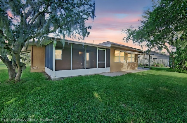 4311 Mandarin Rd, Sebring, FL 33875 - back of house at dusk featuring a lawn and a sunroom
