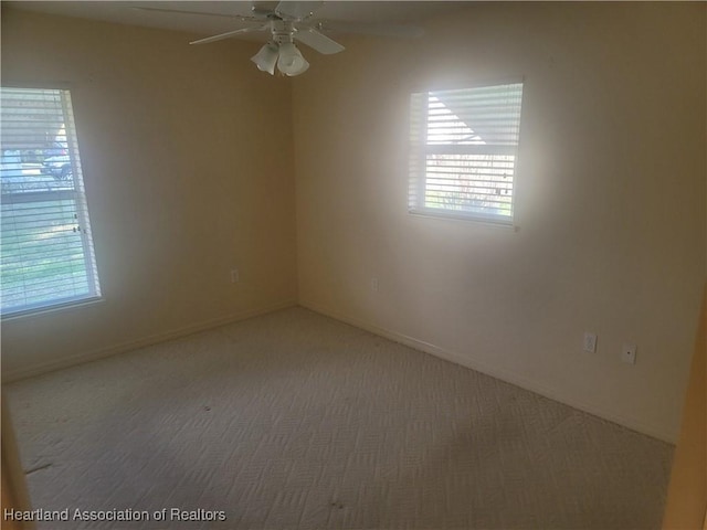 carpeted empty room with ceiling fan and plenty of natural light