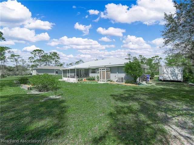 rear view of property with a yard, central AC unit, and a sunroom