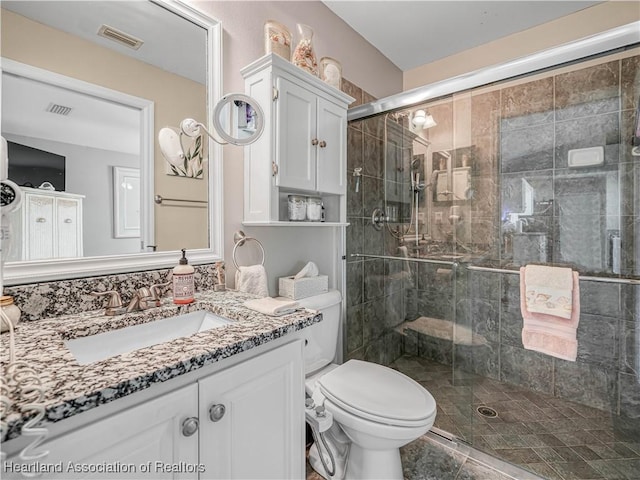 bathroom with visible vents, a shower stall, and vanity