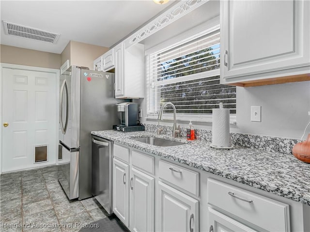 kitchen with visible vents, a sink, light stone countertops, white cabinets, and stainless steel dishwasher