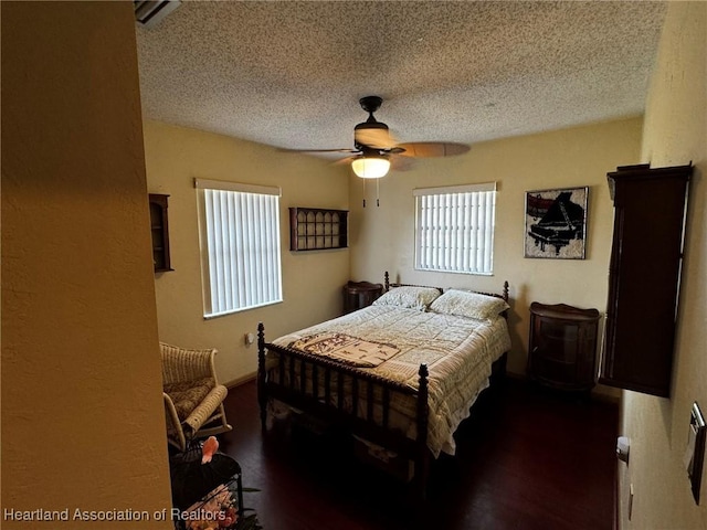 bedroom featuring dark hardwood / wood-style flooring, ceiling fan, and a textured ceiling