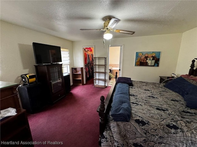 bedroom with a spacious closet, a textured ceiling, a closet, ceiling fan, and carpet