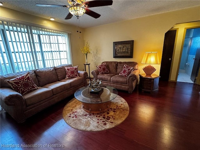 living room with ceiling fan, a textured ceiling, and dark hardwood / wood-style flooring