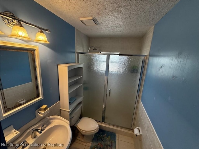 bathroom featuring tile patterned floors, toilet, an enclosed shower, sink, and a textured ceiling