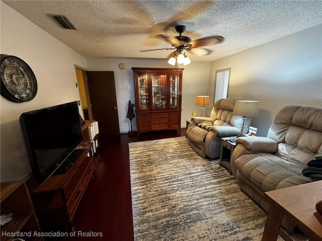 living room with dark hardwood / wood-style floors, a textured ceiling, and ceiling fan