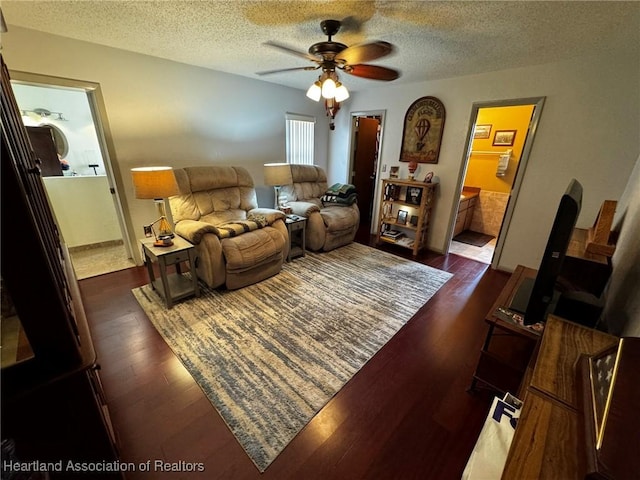 living room with ceiling fan, dark hardwood / wood-style floors, and a textured ceiling