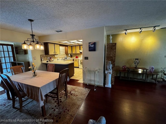 dining space featuring hardwood / wood-style floors, a notable chandelier, and a textured ceiling