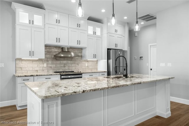 kitchen featuring decorative light fixtures, white cabinetry, and an island with sink