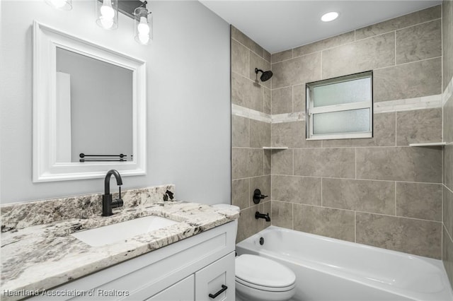 full bathroom with vanity, tiled shower / bath combo, and toilet